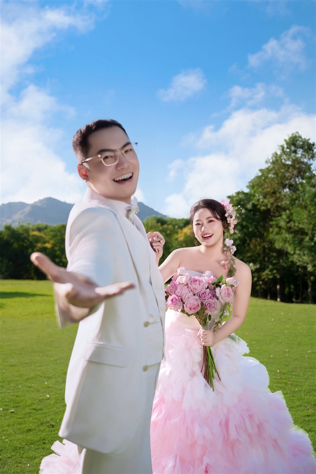 蓝天下，曹健向镜头伸手，王靖涵身着粉色婚纱微笑